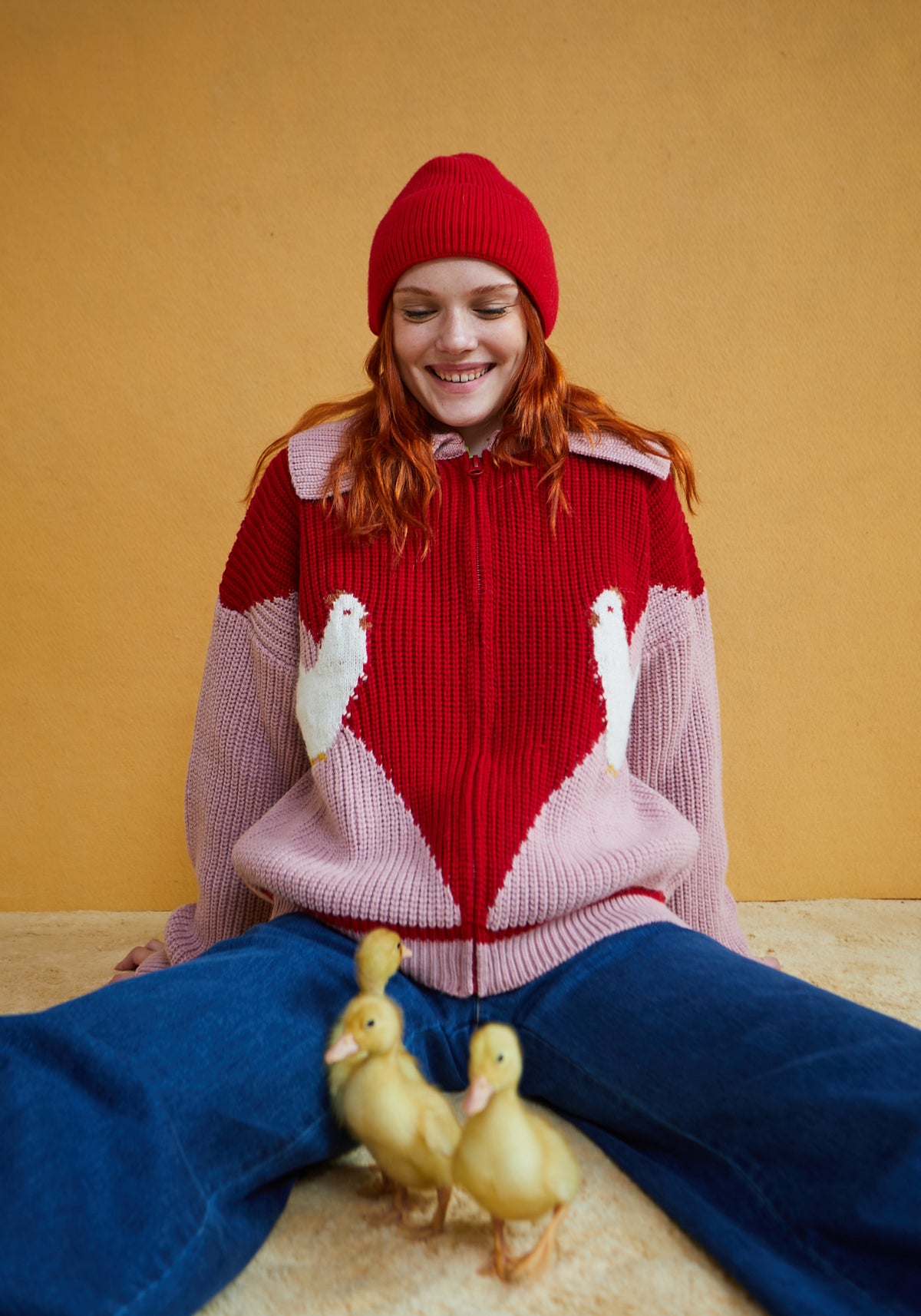 Cárdigan mujer color rosa empolvado y rojo con gallinas blancas, punto grueso, cuello amplio y cierre frontal con cremallera.